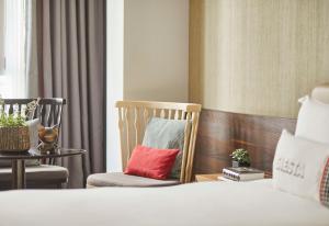a bedroom with two chairs and a bed with a red pillow at Hyatt Centric Gran Via Madrid in Madrid