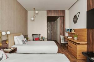 a hotel room with two beds and a desk at Hyatt Centric Gran Via Madrid in Madrid