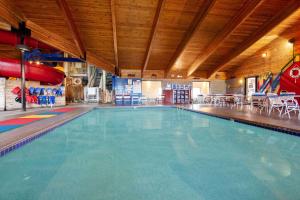a large swimming pool in a building with a slide at AmericInn by Wyndham Ashland in Ashland