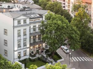 un edificio bianco con un albero di fronte di Bachleda Luxury Hotel Krakow MGallery Hotel Collection a Cracovia