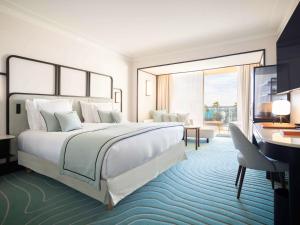 a bedroom with a large white bed and a desk at Mondrian Cannes in Cannes