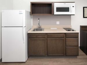 a kitchen with a white refrigerator and a sink at Suburban Studios in Watford City