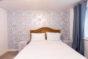 a bedroom with a large white bed with blue wallpaper at Cosy Home in Picturesque Village Cottingham in Cottingham