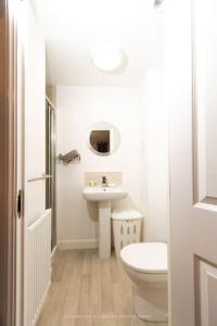 a white bathroom with a toilet and a sink at Cosy Home in Picturesque Village Cottingham in Cottingham