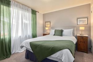 a bedroom with a large bed with green curtains at Jamieson Cottages - Cottage 1 in Howqua
