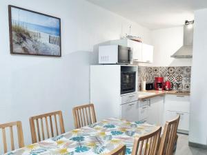 a kitchen with a table with chairs and a white refrigerator at Maison Tita - maison avec parking, jardin et clim in Hyères