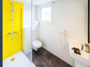 een badkamer met een toilet en een glazen douche bij greet Hotel Nancy Sud in Houdemont
