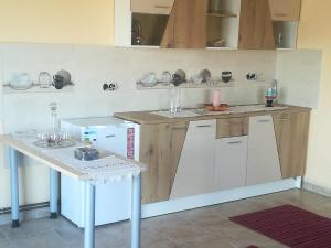 eine Küche mit weißen Schränken und einem weißen Tisch in der Unterkunft Apartement Cristina in Petreştii de Jos