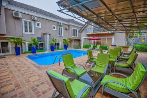a patio with green chairs and a swimming pool at Hamasvile Hotel Utako Abuja in Abuja