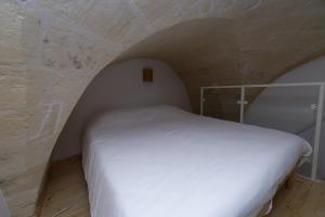 um quarto com uma cama branca numa parede de pedra em Casa Vacanze Ranieri em Grottaglie