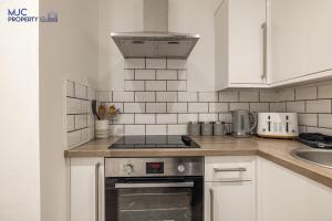 uma cozinha com armários brancos e um forno com placa de fogão em Riverside em Hawick