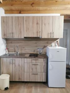 uma cozinha com armários de madeira e um frigorífico branco em Runjini dvori em Kukljica