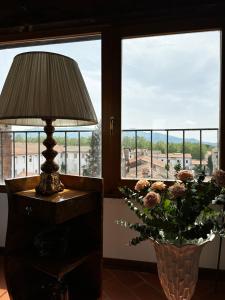 een tafel met een lamp en een vaas met bloemen bij Sunset San Romano in Lucca