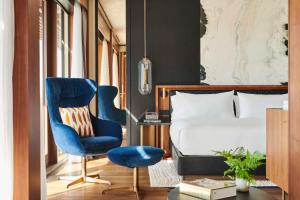 sypialnia z łóżkiem i niebieskim krzesłem w obiekcie Thompson Madrid, by Hyatt w Madrycie