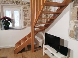 uma sala de estar com uma televisão e uma escada de madeira em Runjini dvori em Kukljica
