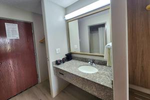 a bathroom with a sink and a mirror at Days Inn by Wyndham Lafayette Scott in Lafayette +17 photos