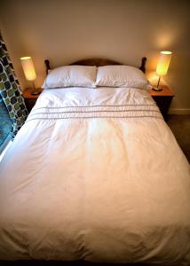 a large white bed with two lamps on two tables at Salisbury 2-bed Luxury Apartment in Salisbury