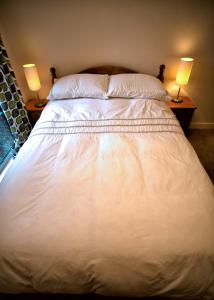 a large white bed with two lamps on two tables at Salisbury Luxury Apartment in Salisbury