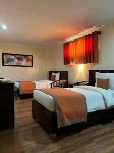 2 Betten in einem Hotelzimmer mit roten Vorhängen in der Unterkunft Subic Residencias in Olongapo