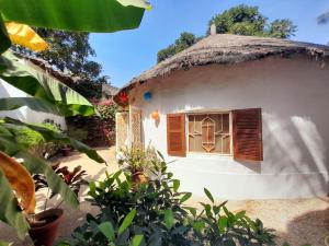 萨利尼亚拉尔Cosy Case avec son Jaccuzi privé Saly的茅草屋顶房屋的外部景观