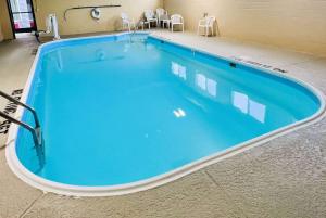 a large swimming pool in a building with blue water at Howard Johnson by Wyndham Urbana in Champaign