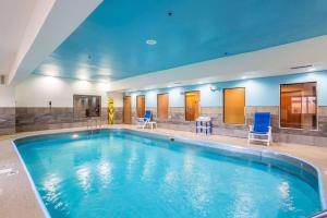 una gran piscina con sillas azules en un edificio en Wingate by Wyndham Owensboro, en Owensboro