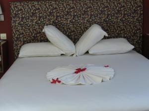 a bed with white pillows and a flower on it at Golden Hill Parker Hotel in Elmina