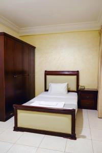 een slaapkamer met een bed met een houten hoofdeinde bij Liberty Avenue Hotel in Doha