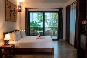 a bedroom with a bed and a large window at MANOLO Beach Resort in Uroa