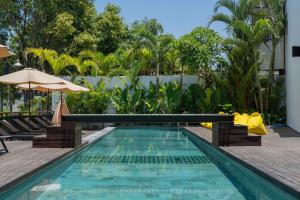 una piscina in un resort con sedie e ombrellone di Sunny Cuddles a Canggu Altre 170 foto