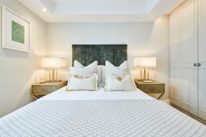 a bedroom with a large white bed with two lamps at Pond Place Apartments in London