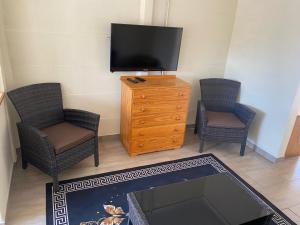 een woonkamer met 2 stoelen en een flatscreen-tv bij Pristine 1 Bed Cottage in Northern suburbs - 2222 in Kingsmead