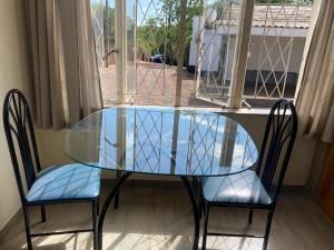 Pristine 1 Bed Cottage in Northern suburbs - 2222 في Kingsmead: طاولة زجاجية وكرسيين أمام النافذة
