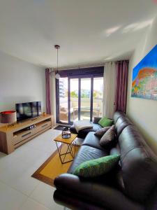 a living room with a leather couch and a television at Arenales Playa 9 by Mar Holidays in Arenales del Sol