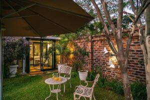 eine Terrasse mit einem Tisch, Stühlen und einem Sonnenschirm in der Unterkunft Kamuzi exquisite tiny home near airport - 2217 in Harare