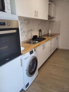 uma cozinha com uma máquina de lavar roupa e um lavatório em APARTAM GRANOLLERS em Granollers