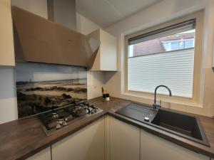 a kitchen with a sink and a stove and a window at Kustverhuur, Park Scheldeveste Zwin 065 in Breskens