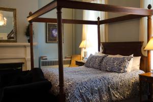 Bourbon Manor Bed & Breakfast Inn في باردستاون: غرفة نوم بسرير مع مظلة خشبية