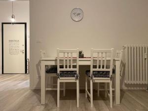 a white table with three chairs and a clock on a wall at La Casa di Mimmi in Mantova