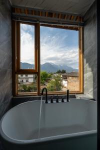 a bath tub in a bathroom with a window at Lijiang Shitian B&B in Lijiang