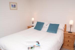 une chambre avec un lit blanc avec des oreillers bleus dans l'établissement Dozmary Cottage, à Launceston
