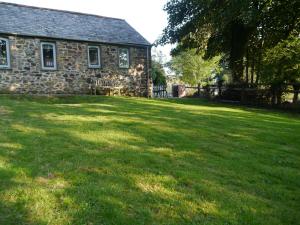 une vieille maison en pierre avec une grande cour gazonnée dans l'établissement Dozmary Cottage, à Launceston