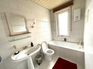 a bathroom with a sink and a toilet and a tub at KobyHome Apartment in Enger