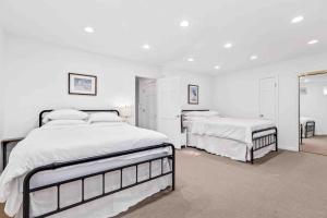 a white bedroom with two beds and a mirror at Riverview Retreat On Warehouse Creek in Edgewater