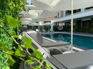 a swimming pool with chairs and umbrellas next to a building at Sam Hotel in Antalya