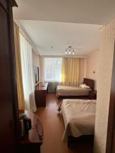 a hotel room with two beds and a window at Hotel Alma-Ata in Borovoye