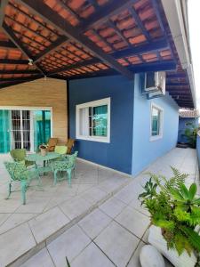 un patio con mesa, sillas y una pared azul en casa no paraíso do Capri, en São Francisco do Sul