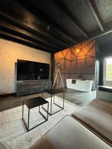 een woonkamer met een bad, een tv en een tafel bij Luxury Loft in Velddriel