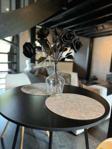 una mesa negra con un jarrón de rosas. en Luxury Loft, en Velddriel