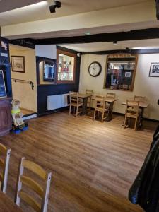 a restaurant with tables and chairs and a clock on the wall at Ring O Bells in Chagford